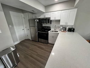 Una cocina moderna con electrodomésticos de acero inoxidable, armarios blancos y encimera con vetas.
