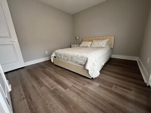 A bedroom with a bed, a nightstand, and a door.