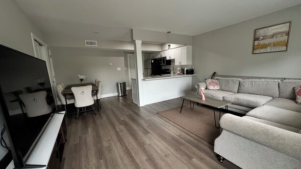 Una sala moderna con sofá, televisión, mesa de comedor y zona de cocina.