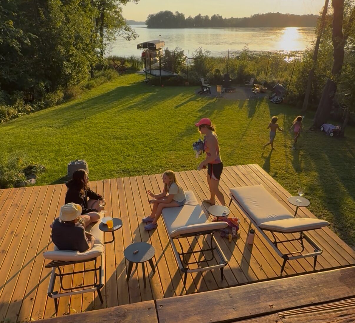 Eine Terrasse mit Liegestühlen, einem kleinen Tisch und Blick auf einen See.