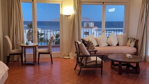 Een hotelkamer met een balkon, een bank, een tafel en stoelen.