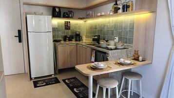 Uma cozinha compacta com geladeira, cafeteira e área de refeições com banquetas.