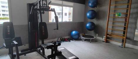 Un gimnasio con equipo de ejercicio, una ventana y una escalera.