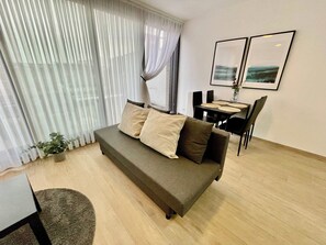 Un salon moderne avec un canapé, une table à manger, des chaises, une petite plante en pot et deux tableaux encadrés accrochés au mur.
