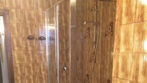 Une douche avec une porte en verre, une plante en pot et un porte-serviette.