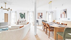 Ein geräumiges Wohnzimmer mit einer Couch, einem Essbereich mit Holztisch und einem großen Fenster.