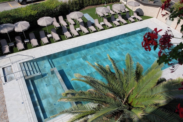 Piscina a l'aire lliure de temporada, para-sols i gandules