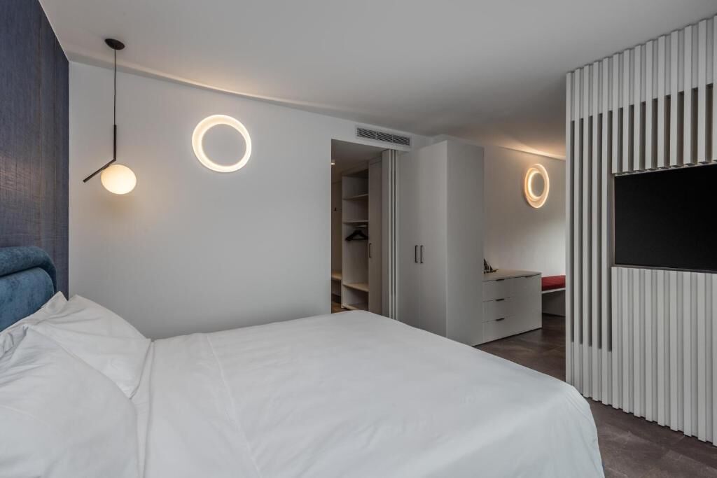 A modern bedroom with a bed, a wardrobe, and a TV.
