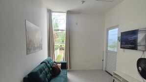 A modern living room with a green sofa, a flat-screen TV, and a ceiling fan. - Complete house 15 minutes from beaches in Aquiraz (Tapera)