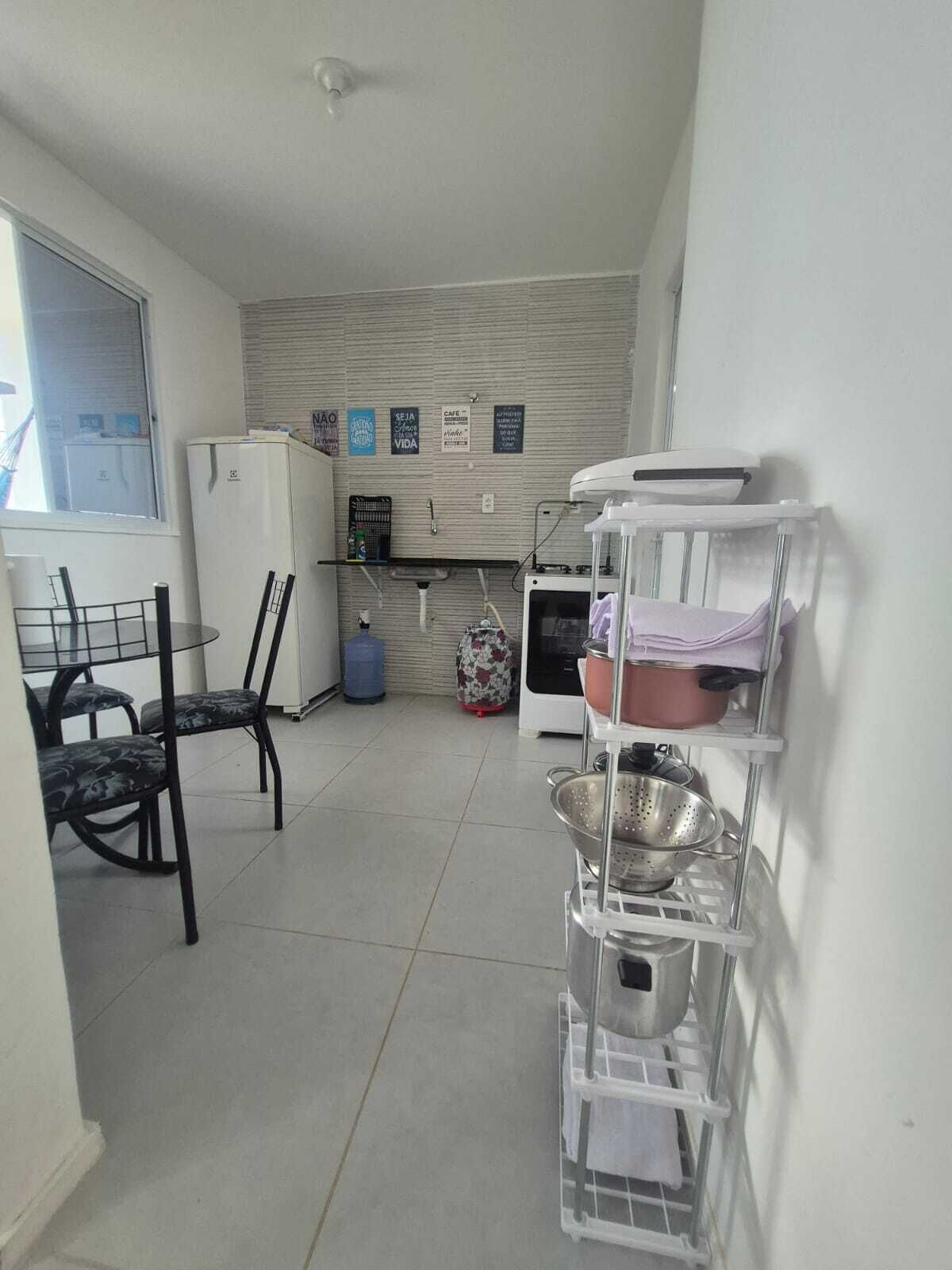 Une cuisine compacte équipée d’un réfrigérateur, d’un distributeur d’eau, d’un évier et d’une cuisinière. On y trouve également des chaises et une table dans l’espace repas attenant.