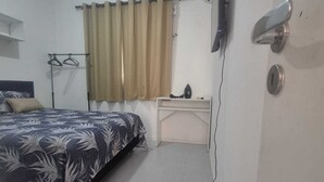 A bedroom with a bed, a desk, a TV, and a window with curtains. - Complete house 15 minutes from beaches in Aquiraz (Tapera)
