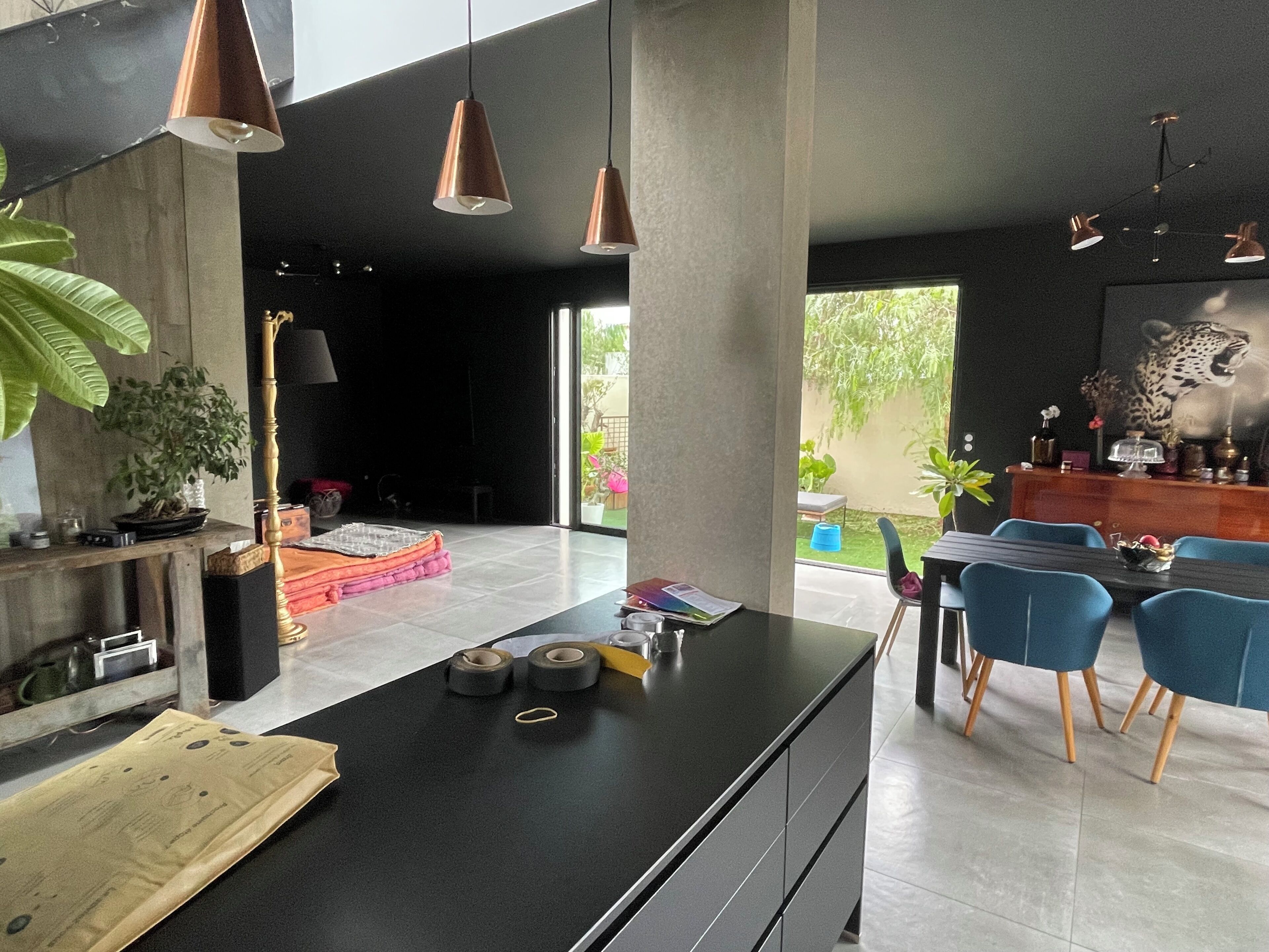 A modern kitchen with a central island, pendant lighting, and a dining area with blue chairs.