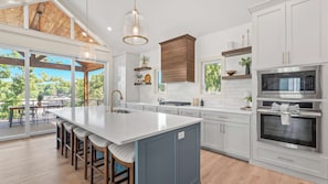 A modern kitchen with a large island, stainless steel appliances, and a view of the outdoors.