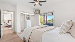 A bedroom with a bed, a ceiling fan, a wardrobe, and a view of the outdoors. - The Blue Sapphire - Dock, Hot Tub & Fire Pit (Sunrise Beach)