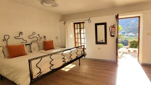 A bedroom with a bed, a desk, a chair, a window with a view, and a fire extinguisher. - Casa Lara Hermigua - Studio ESTAMBUL with terrace - Ideal for families (Hermigua)