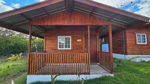 A wooden house with a porch, a window, and a door.