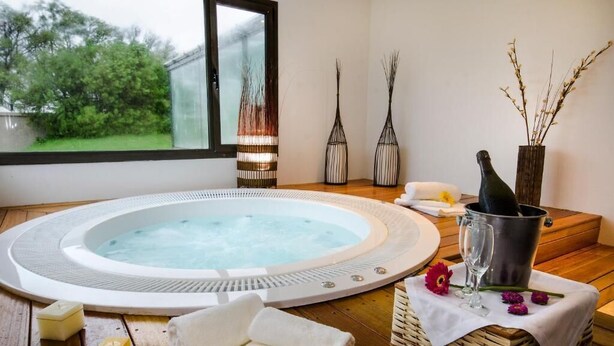 Ett bubbelbad med ett träbord, ljus och en flaska champagne.