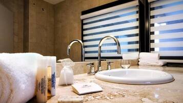 A bathroom with a sink, two faucets, a towel, a soap dispenser, and a mirror.