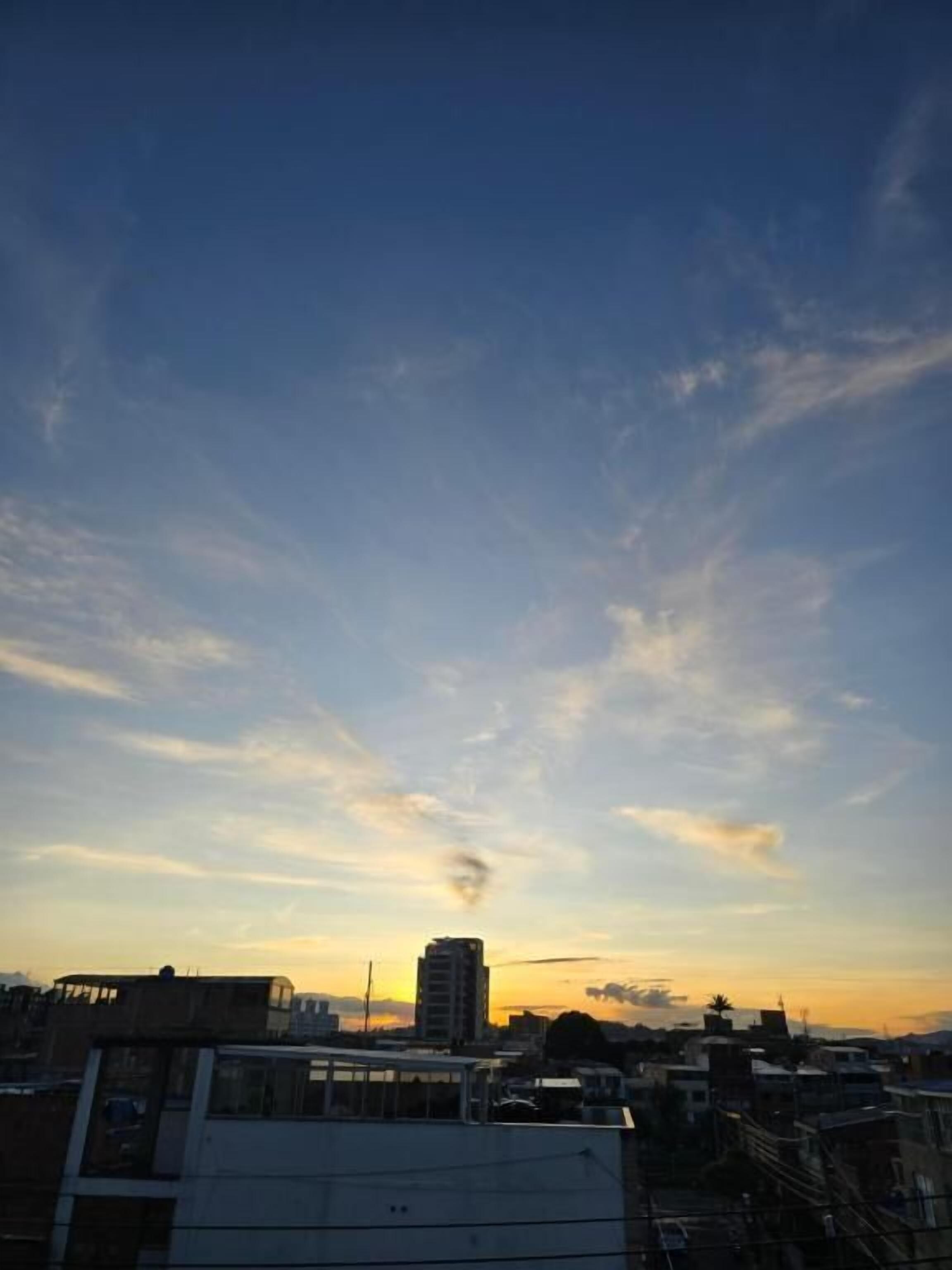 A cityscape during sunset with buildings and a clear sky.