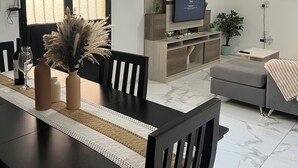 A modern living room with a TV, sofa, dining table, chairs, and a potted plant. - Casa completa 2 habitaciones 2 baños a 7 minutos del aeropuerto y 5 de la ciudad (Guaymallen)