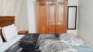 Ein Schlafzimmer mit einem Bett, einem Holzschrank und einem Spiegel an der Wand.
