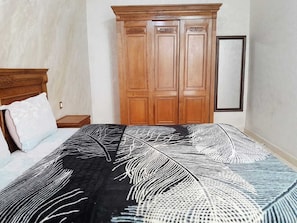 Ein Schlafzimmer mit einem Bett, einem Holzschrank und einem Spiegel an der Wand.