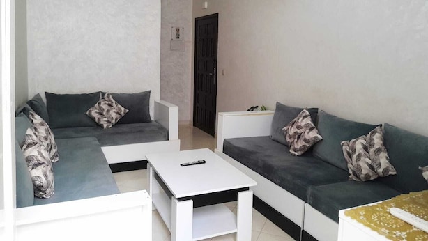 Ein modernes Wohnzimmer mit zwei grauen Sofas, einem weißen Couchtisch und einem kleinen weißen Beistelltisch.
