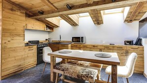 A wooden interior with a dining table, chairs, a bench, and a kitchen area with appliances. - Cozy 2bdr/5p Apartment Near the ski Slopes (Megeve)