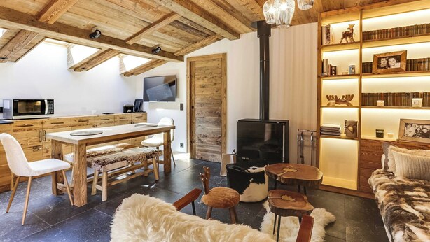 A cozy living room with a wooden ceiling, a fireplace, a bookshelf, and a dining area with a table and chairs. - Cozy 2bdr/5p Apartment Near the ski Slopes (Megeve)