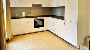 A modern kitchen with white cabinets, a black oven, and a wooden floor. - Leemstraat Chic Escape for Four (Antwerp)