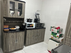 Eine kompakte Küche mit Mikrowelle, Mixer und Kühlschrank.