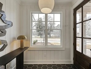 Ein Zimmer mit einem großen Fenster, einem schwarzen Konsolentisch und einer Wandlampe.