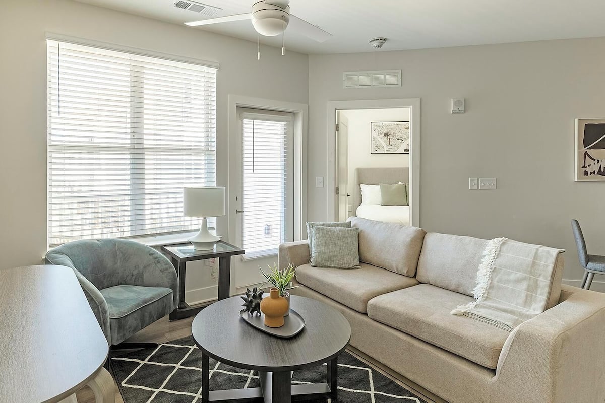 A living room with a sofa, armchair, coffee table, and a TV.