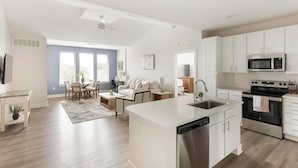 A modern kitchen with a dishwasher, stove, and microwave. There is a dining area with a table and chairs. - Landing Apartments Huntsville near Lake Forest (Huntsville)