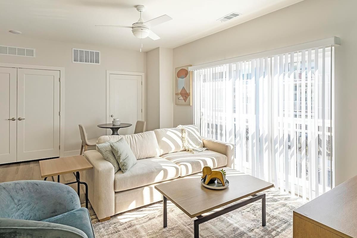 A modern living room with a sofa, a coffee table, a chair, and a ceiling fan.