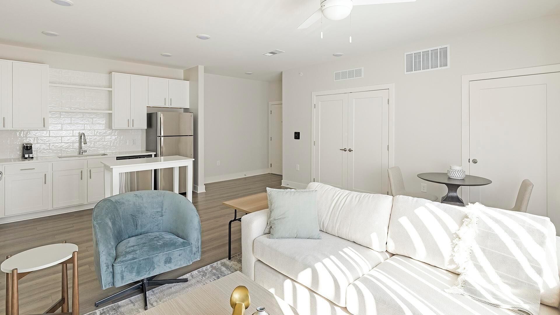 A modern living space with a kitchen, a dining area, and a seating area with a sofa and armchairs.