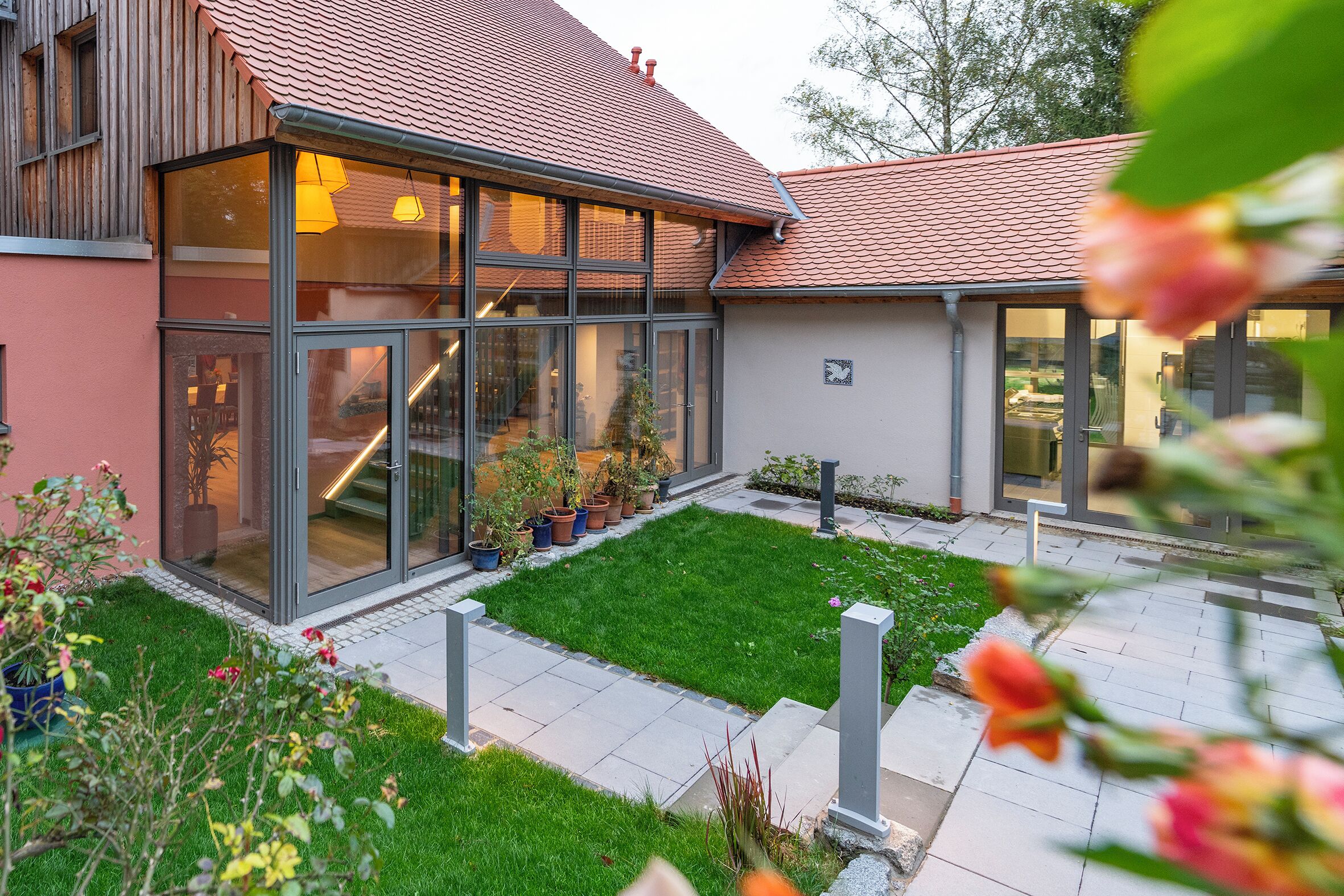 Et moderne hus med store vinduer, en velplejet græsplæne og et tag med teglsten.