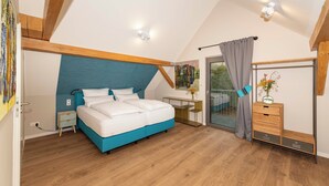 Quarto com cama, mesa de cabeceira, cômoda e vista através de uma porta de vidro.