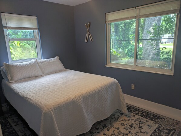 A bedroom with a bed, two windows, and a rug. - Quiet Court, Near NAS, Downtown, & Beaches. View of Blue Angels practice! (Pensacola)