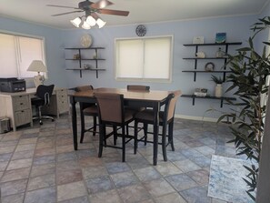 A dining area with a table and chairs, a ceiling fan, and shelves with decorative items. - Quiet Court, Near NAS, Downtown, & Beaches. View of Blue Angels practice! (Pensacola)