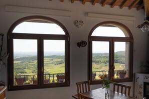 Ein Zimmer mit zwei großen Bogenfenstern und Blick auf eine grüne Landschaft.