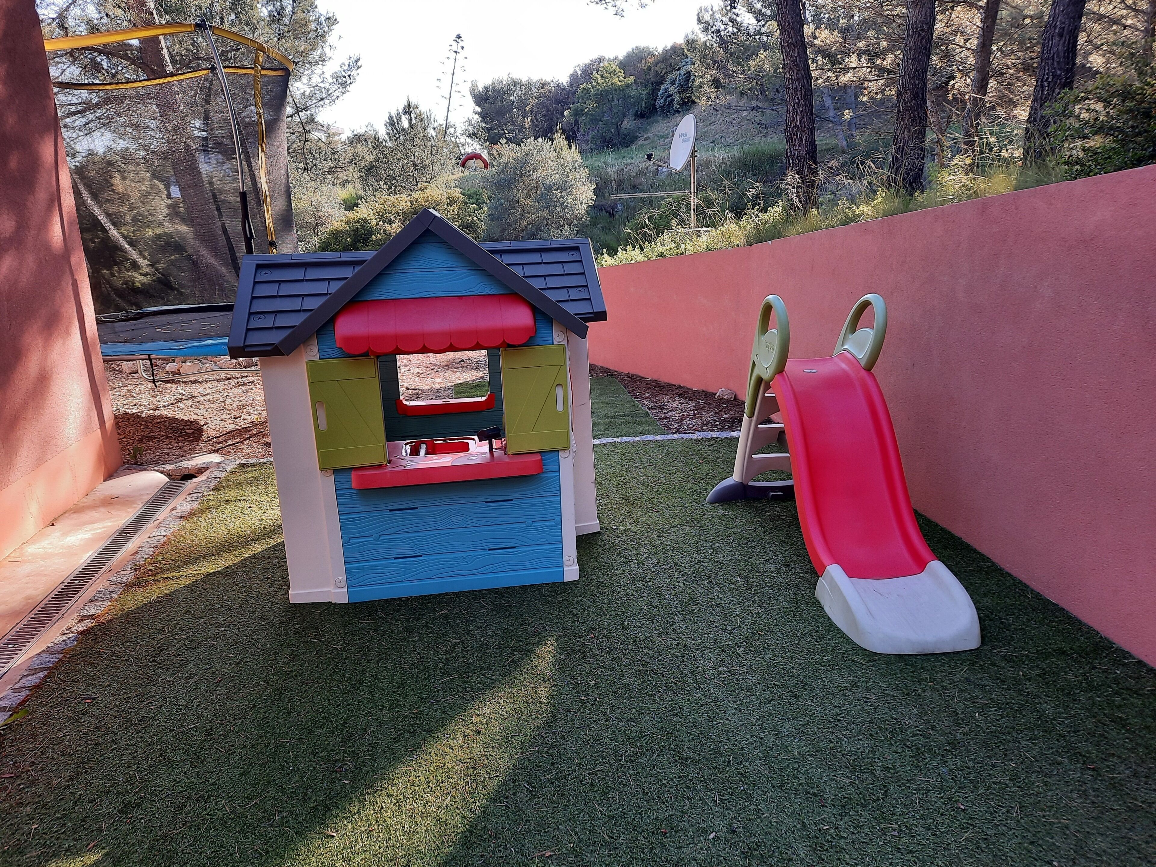 A children's play area with a small house, a slide, and a climbing structure.