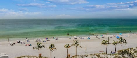 Une plage avec des palmiers, des parasols et des gens.