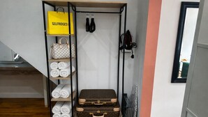A storage unit with a yellow bag, rolled towels, handbags, and suitcases. - Comfortable 1-bed Chester Apartment with Parking & Full Kitchen, Home from Home (Chester)