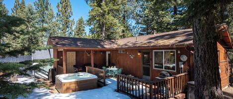 Une cabane avec un bain à remous, une terrasse et une vue sur de grands pins.