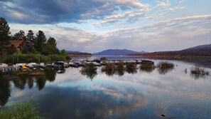 A calm lake with docked boats, a house on the left, and mountains in the background. - Hot Tub Under the Stars • Trails Out Your Door (Big Bear Lake)