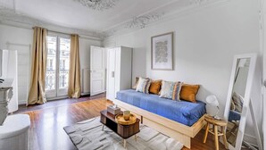 Un dormitorio con cama, mesita de noche, espejo y ventana con cortinas.