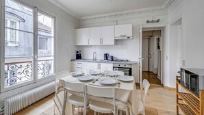Una cocina moderna con armarios blancos, una mesa de comedor para cuatro personas y vistas amplias a través de grandes ventanales.
