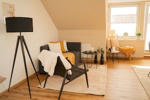 A cozy living room with a sofa, a chair, a floor lamp, and a small table with candles. - Arrive & Feel at Home • Fireplace • calm • Parking Lot (Paderborn)