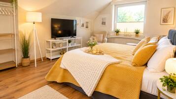 Une chambre à coucher avec un lit, une télévision, une fenêtre et une plante.
